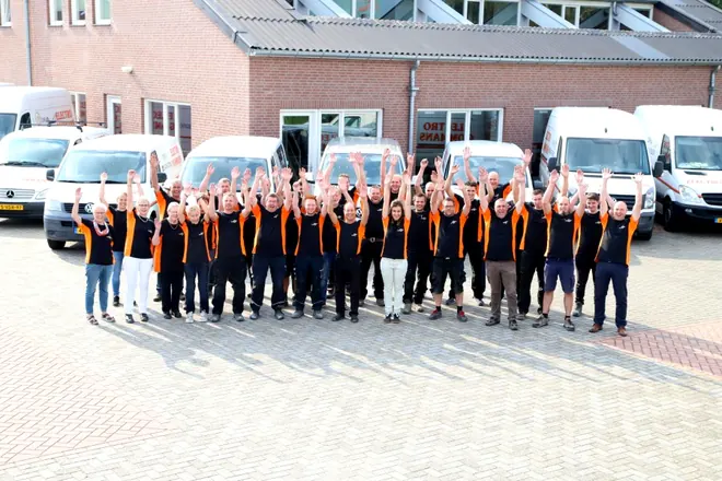 Het team van Electro Gommans in bedrijfskleding voor het pand en de bedrijfsbussen